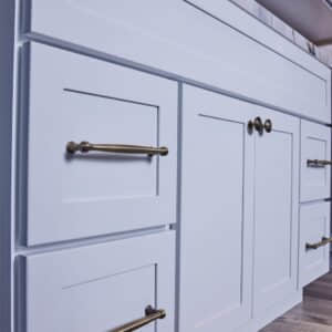White kitchen cabinets with brass handles and knobs.