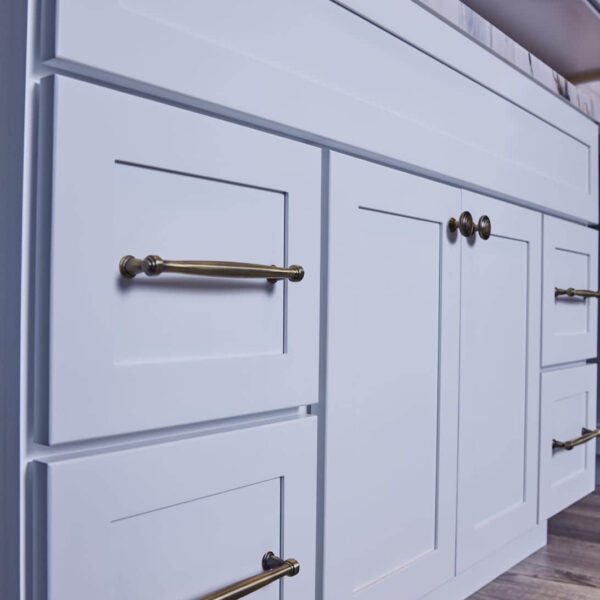 White kitchen cabinets with brass handles and knobs.