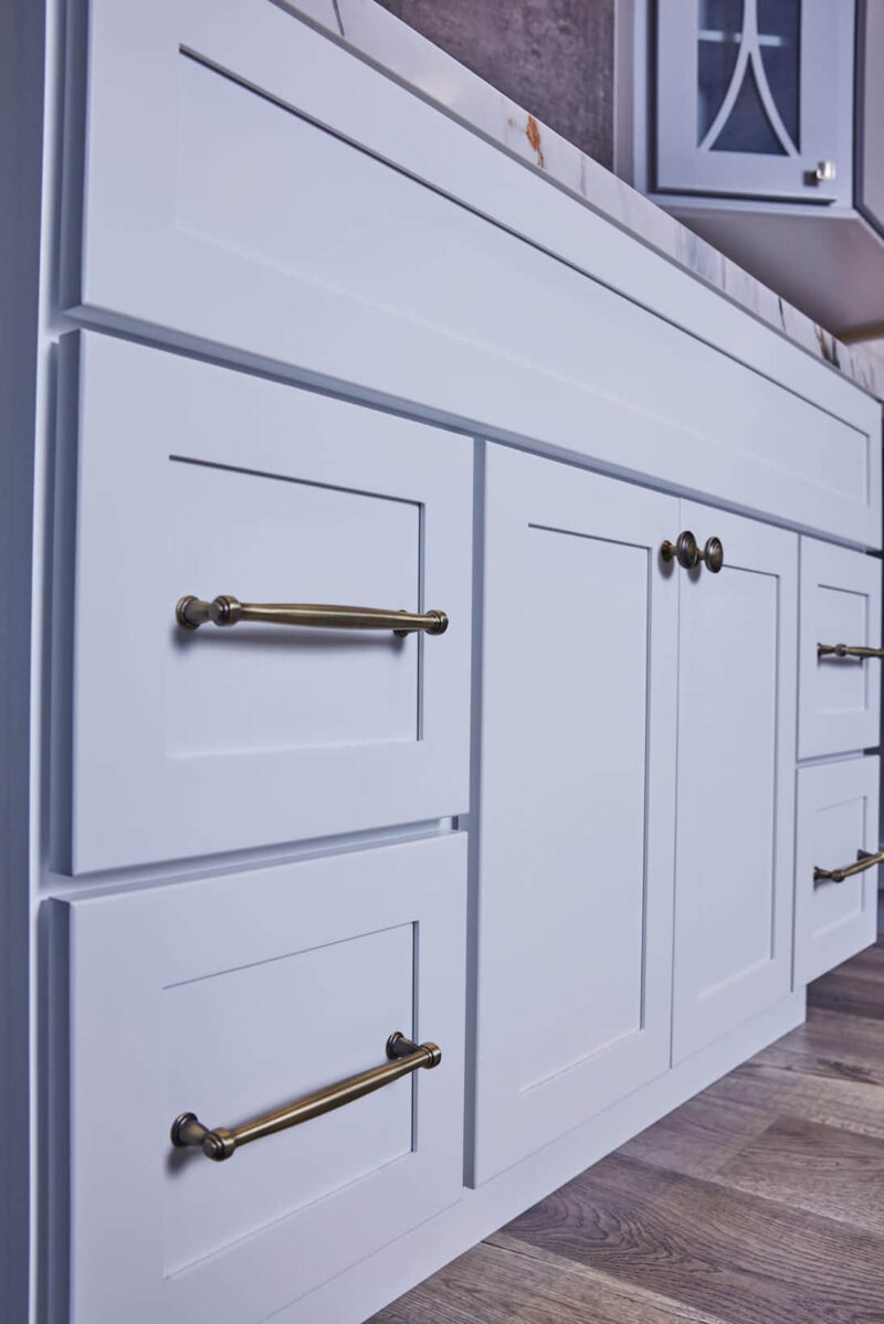 White kitchen cabinets with brass handles and knobs.