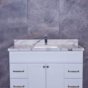 White bathroom vanity with marble countertop against gray stone wall.