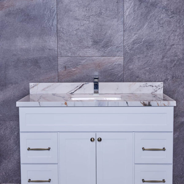 White bathroom vanity with marble countertop against gray stone wall.