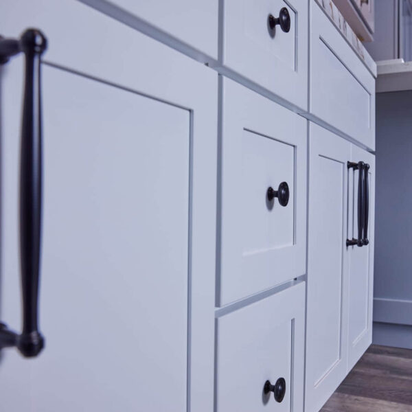 White kitchen cabinets with black handles, close-up view.