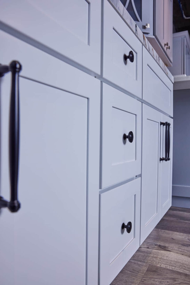 White kitchen cabinets with black handles, close-up view.