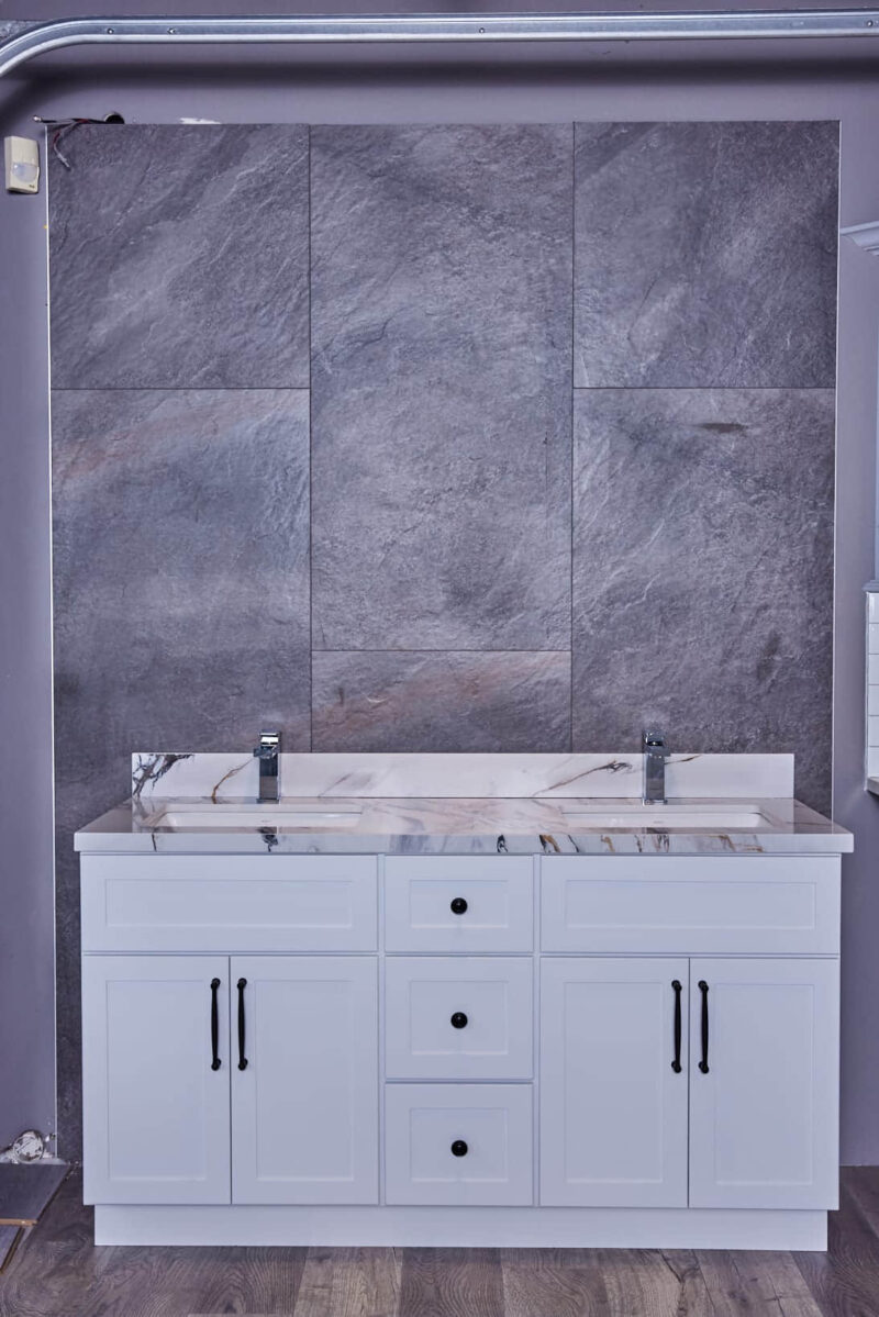 White bathroom vanity with marble countertop against gray stone wall.