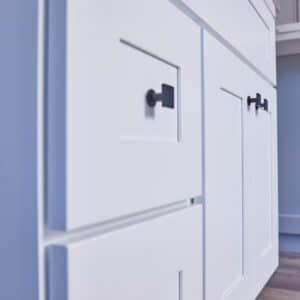 White kitchen cabinets with black handles, close-up view.