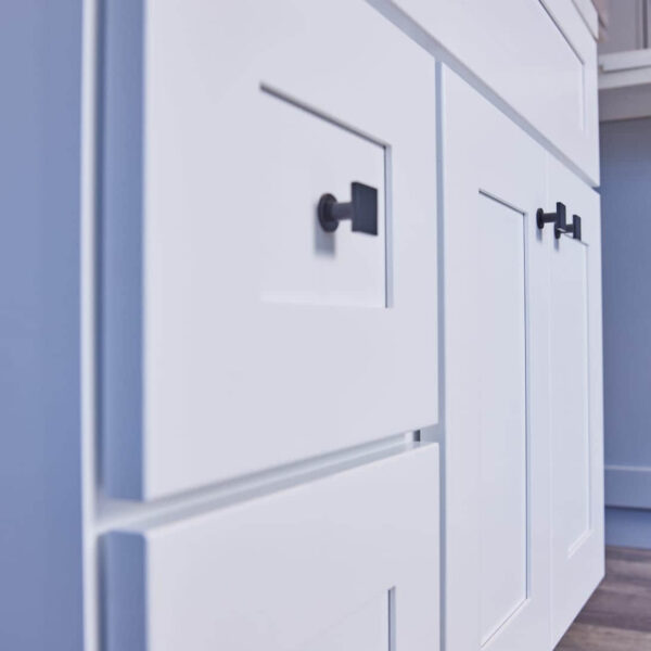White kitchen cabinets with black handles, close-up view.