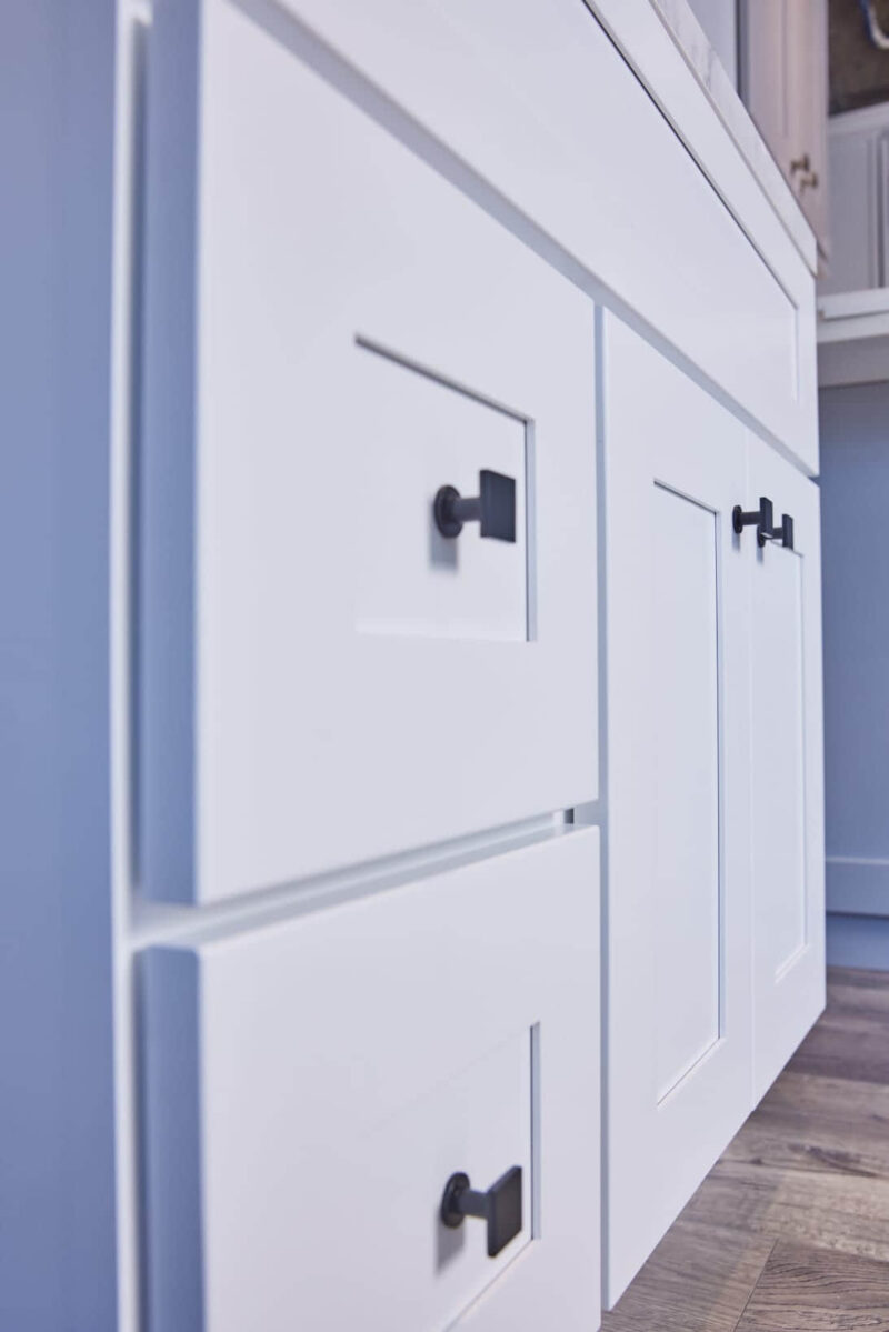 White kitchen cabinets with black handles, close-up view.