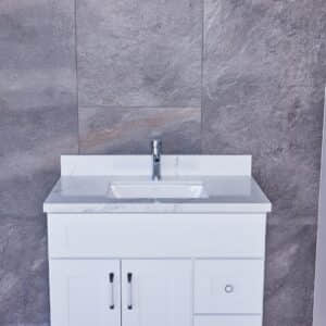 White bathroom vanity with marble countertop against gray stone wall.