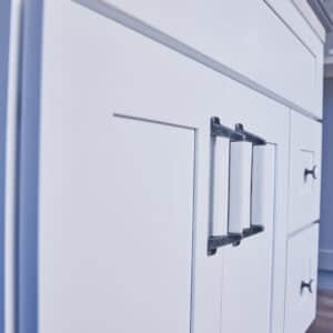 White kitchen cabinet with modern black handles.