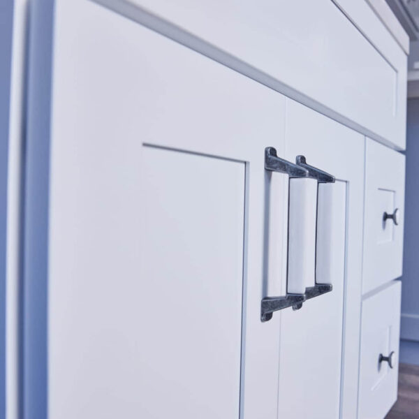 White kitchen cabinet with modern black handles.