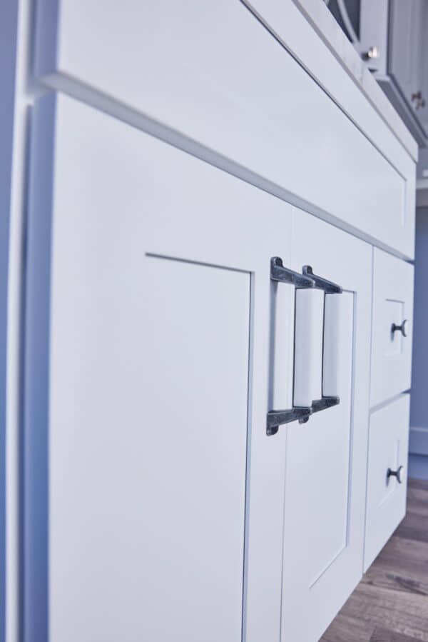 White kitchen cabinet with modern black handles.