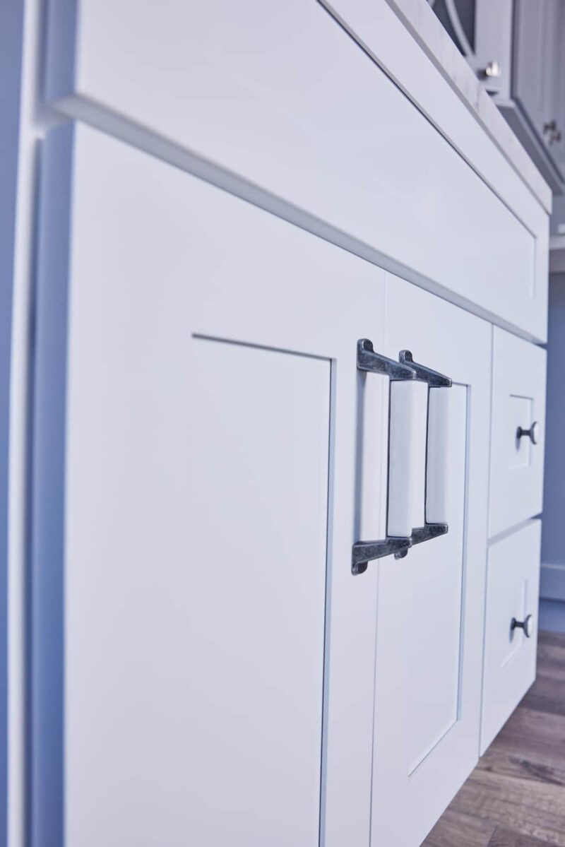 White kitchen cabinet with modern black handles.