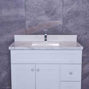 White bathroom vanity with marble countertop against gray stone wall.