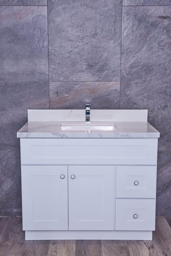 White bathroom vanity with marble countertop against gray stone wall.
