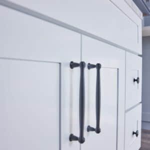 White kitchen cabinet with black handles, close-up view.