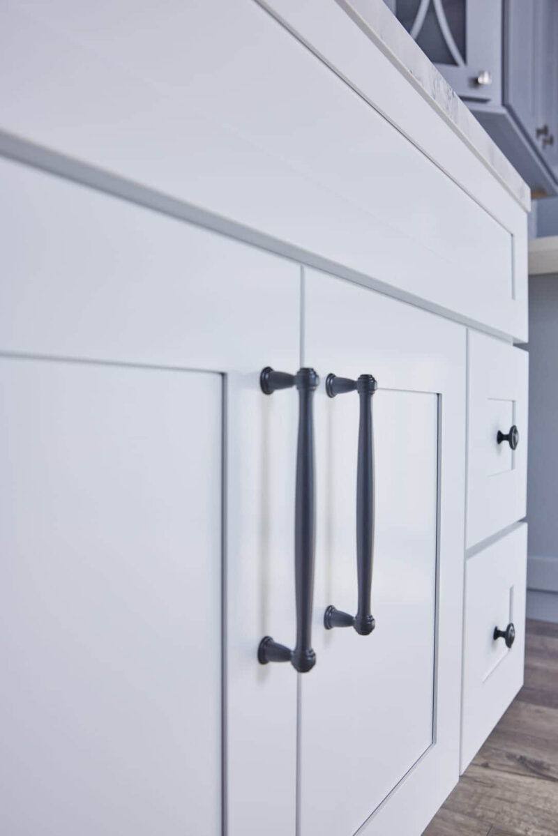 White kitchen cabinet with black handles, close-up view.