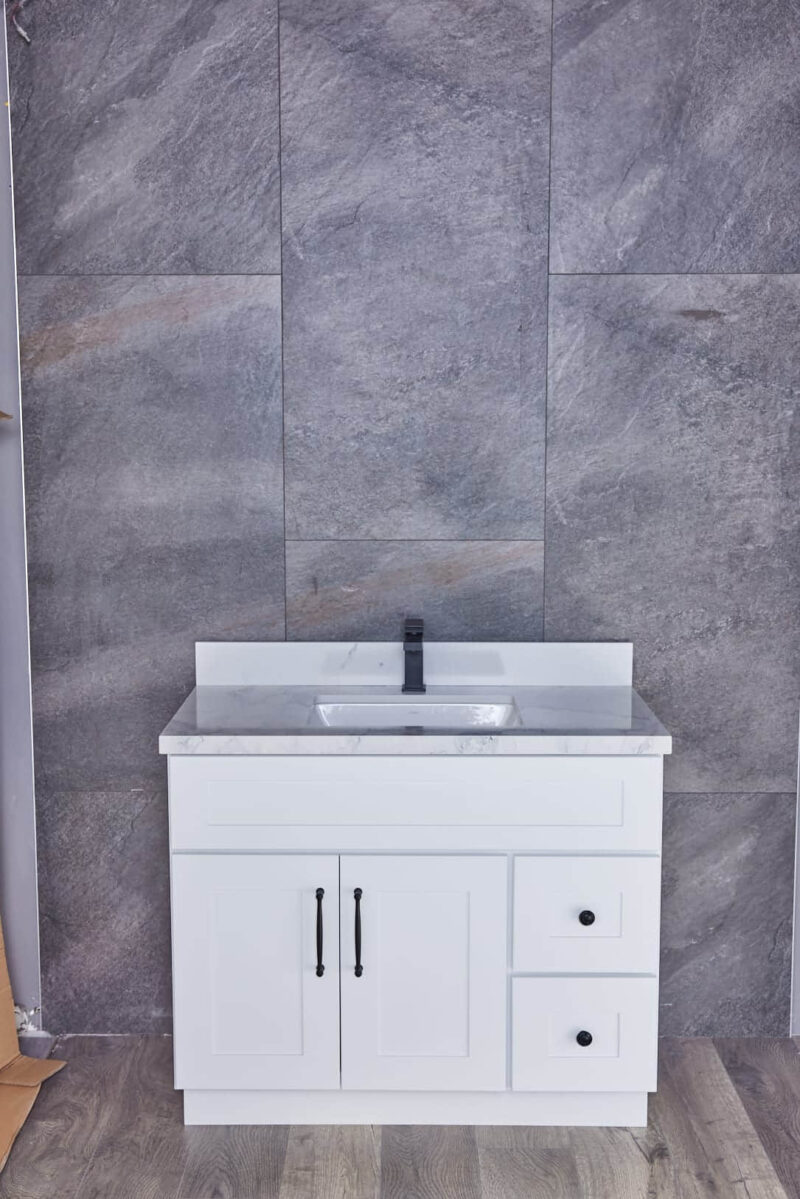 White bathroom vanity with marble countertop against gray tiled wall.