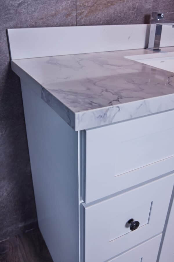 White bathroom vanity with marble countertop and modern faucet.