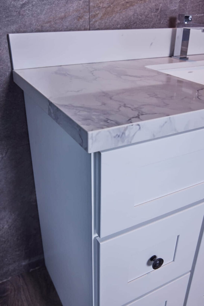 White bathroom vanity with marble countertop and modern faucet.