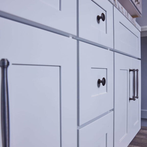 White kitchen cabinets with black handles, close-up view.