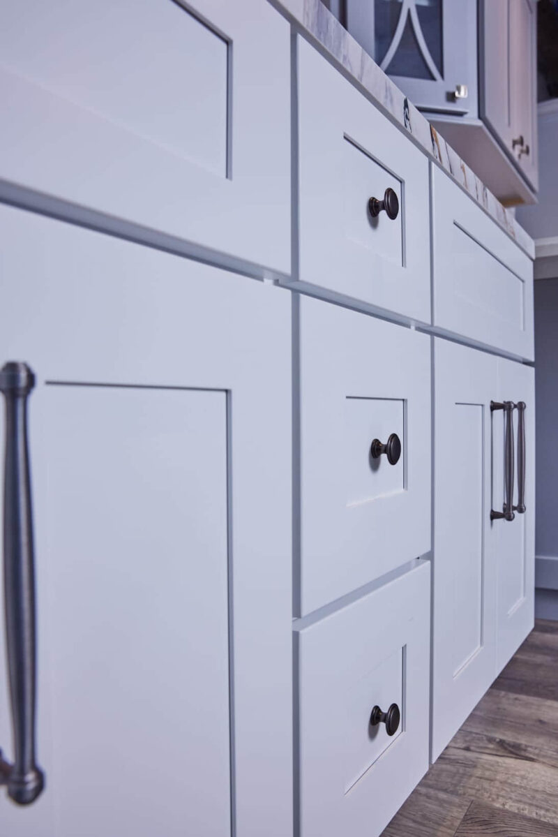 White kitchen cabinets with black handles, close-up view.