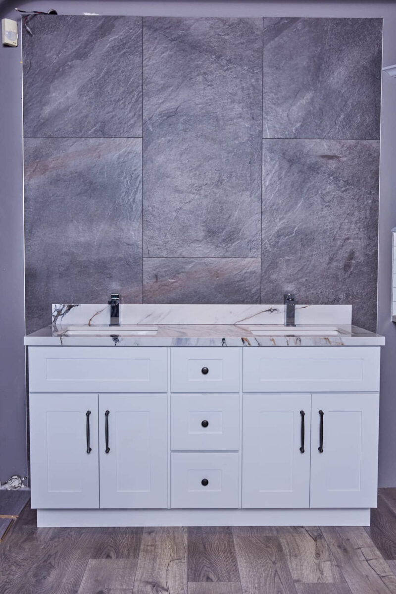 White bathroom vanity with marble countertop and gray tiled wall background.