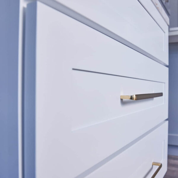 White kitchen drawers with sleek gold handles.