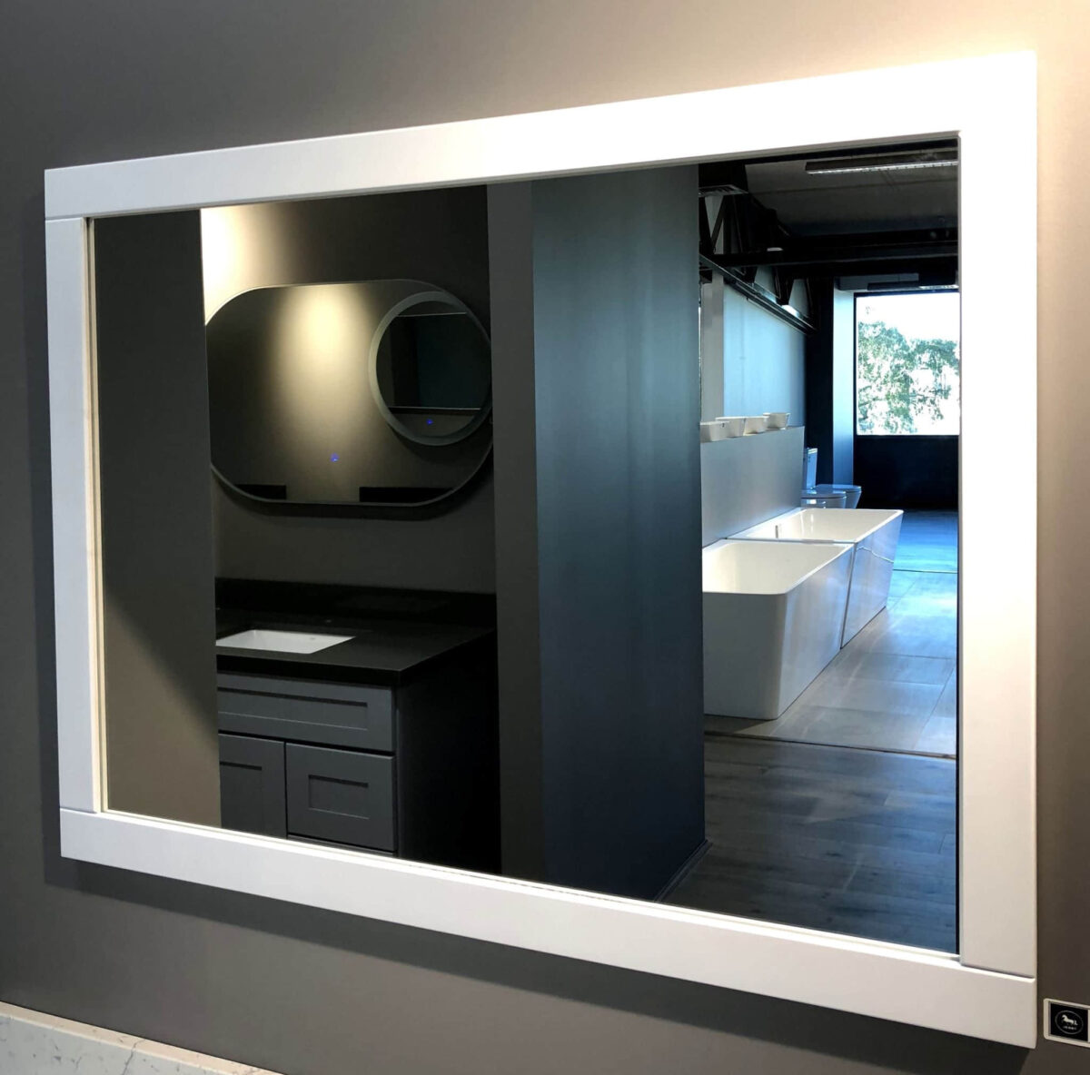 Modern bathroom showroom with large mirror and sleek fixtures.