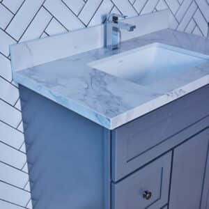 Marble countertop with sink and blue cabinet against herringbone tile wall.