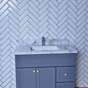 Blue bathroom vanity with marble countertop and herringbone tile wall.