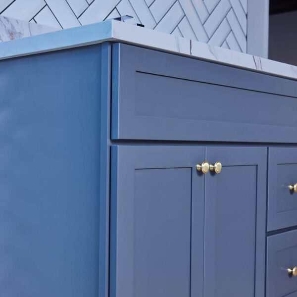 Blue kitchen cabinet with gold knobs and marble countertop.