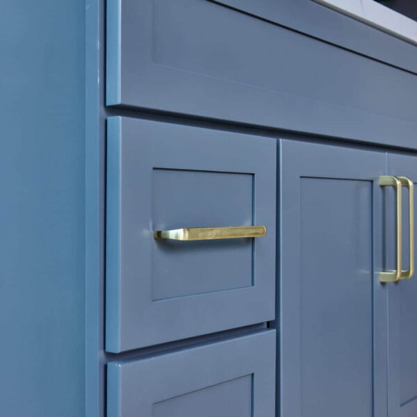 Blue kitchen cabinet with gold handles and marble countertop.
