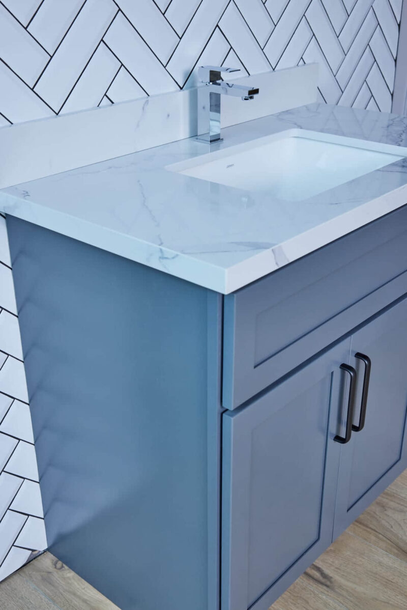 Blue bathroom vanity with marble countertop and modern handles.