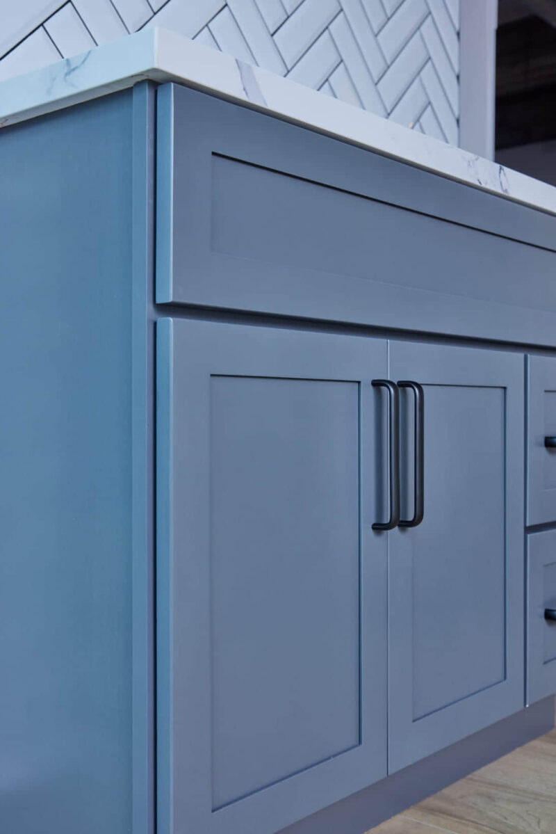 Blue kitchen cabinet with black handles.