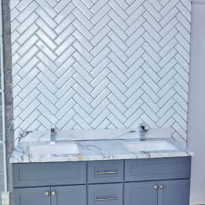 Modern bathroom with herringbone tile backsplash and double sink vanity.