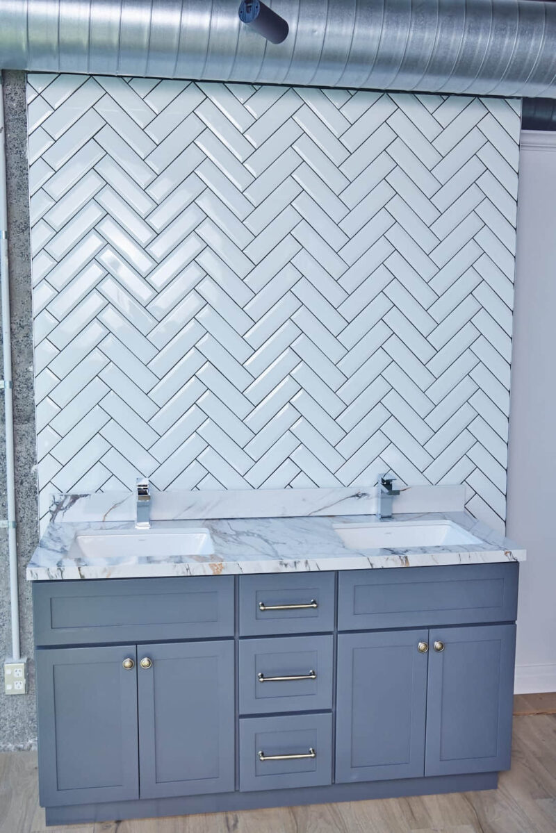 Modern bathroom with herringbone tile backsplash and double sink vanity.