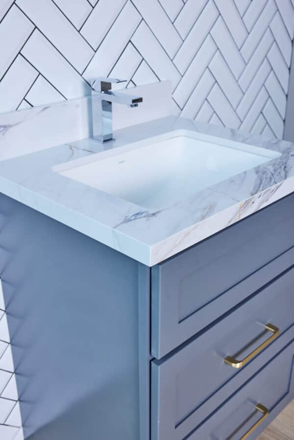 Modern bathroom vanity with marble countertop and herringbone tile backsplash.
