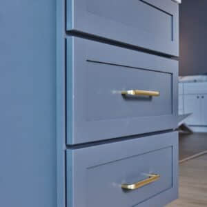 Blue kitchen cabinets with gold handles in modern design.