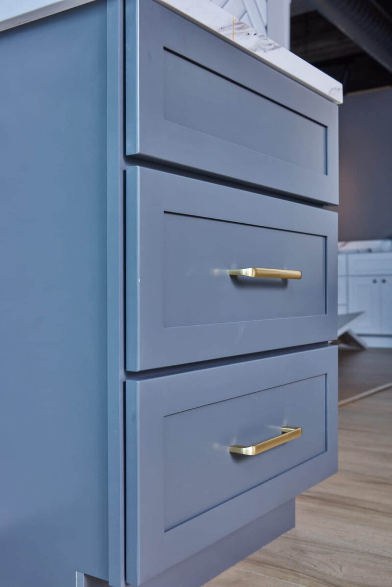 Blue kitchen cabinets with gold handles in modern design.