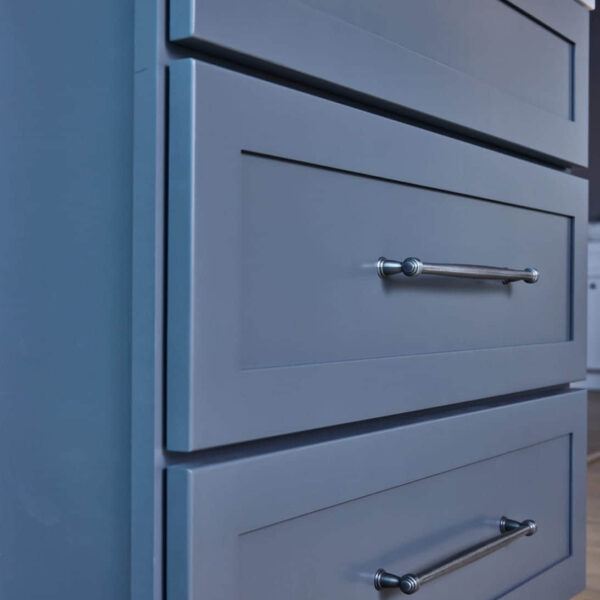Blue kitchen cabinets with silver handles and marble countertop.