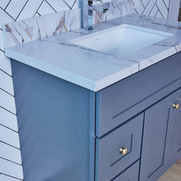 Blue bathroom vanity with marble countertop and herringbone tile backsplash.