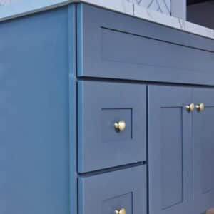 Blue kitchen cabinets with gold knobs and marble countertop.