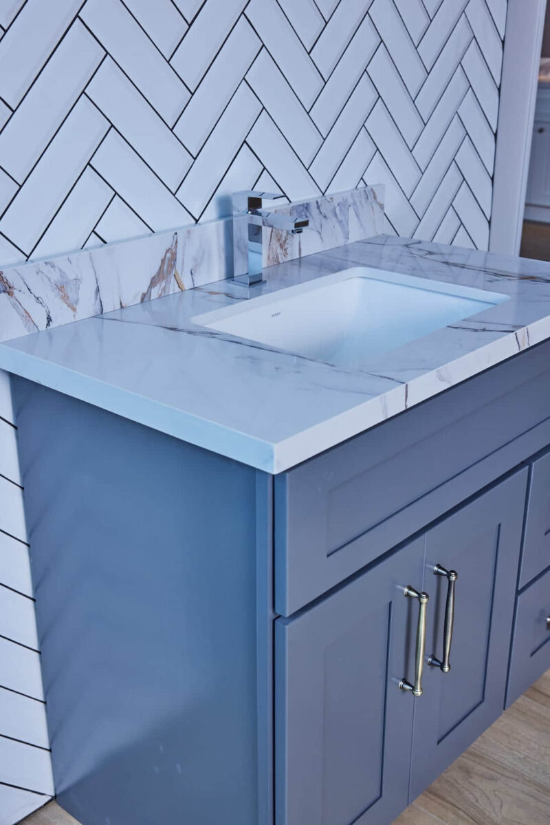 Modern bathroom vanity with marble countertop and blue cabinet.