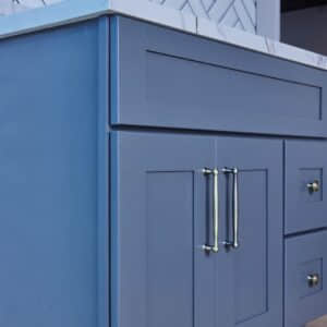 Blue kitchen cabinet with marble countertop and silver handles.