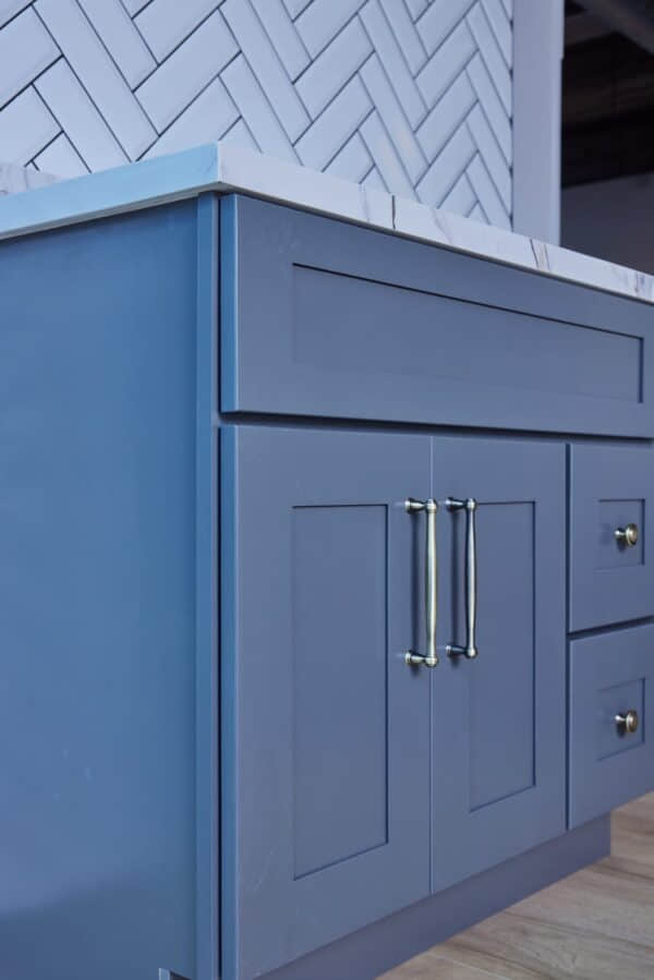 Blue kitchen cabinet with marble countertop and silver handles.