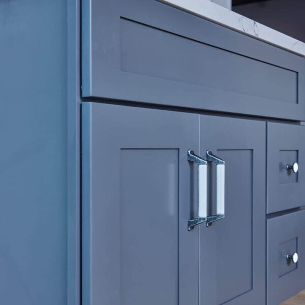 Blue kitchen cabinet with marble countertop and herringbone backsplash.