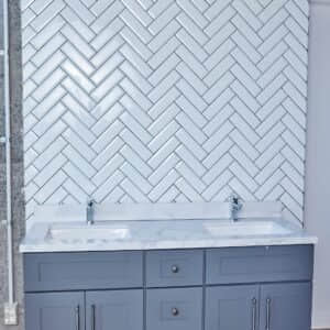 Modern kitchen with herringbone tile backsplash and gray cabinets.