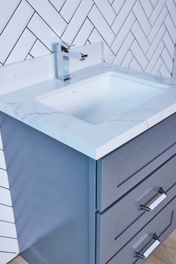 Modern bathroom vanity with marble countertop and herringbone tile backsplash.