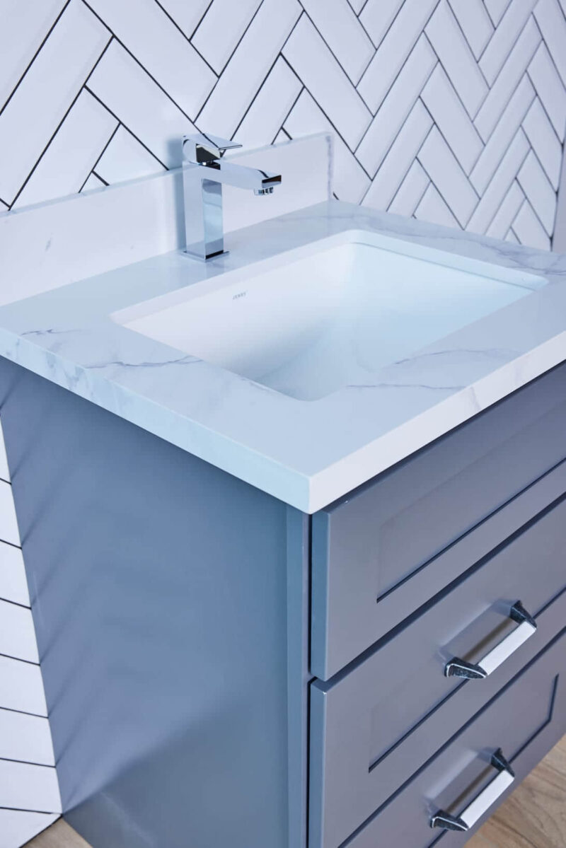 Modern bathroom vanity with marble countertop and herringbone tile backsplash.