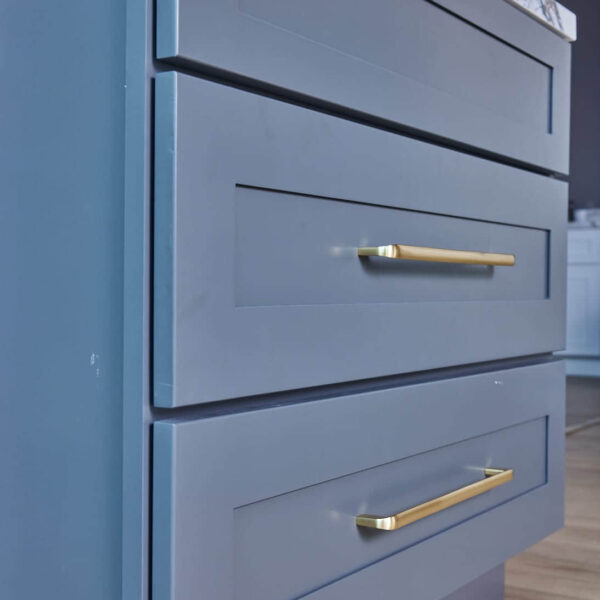 Gray bathroom vanity with marble countertop and herringbone tile backsplash.
